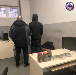 narkotyki w woreczkach i słoikach lezące na stole obok policjant z zatryzmanym