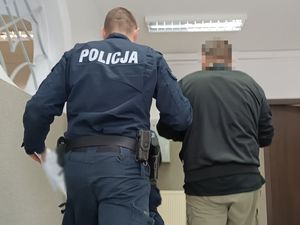 policjant prowadzi zatrzymanego męzczyzne do celi