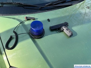 broń i sygnalizator policyjny na masce samochodu