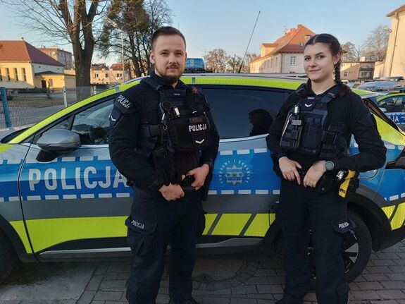 POLICJANT I POLICJANTKA STOJĄ PRZY RADIOWOZIE