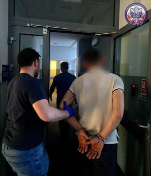 policjant prowadzi zatrzymanego