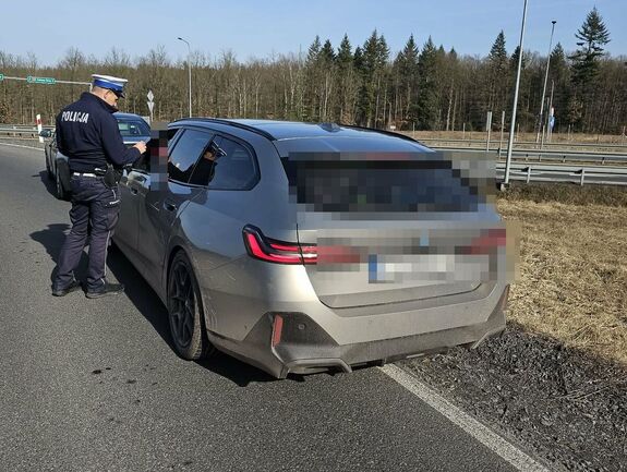 policjant kontroluje kierowcę siedzącego w samochodzie osobowym