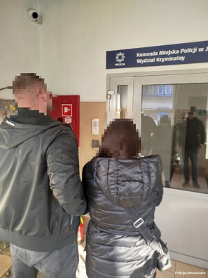 policjant prowadzi zatrzymaną kobietę