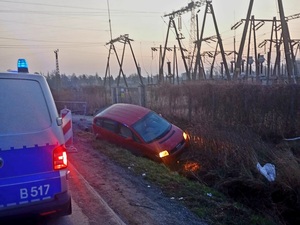 samochód osobowy w rowie  na drodze stoi radiowóz