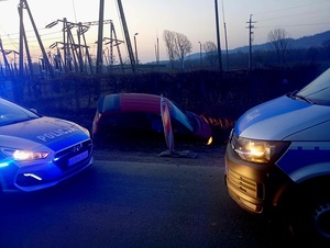 samochód osobowy w rowie na drodze stoją dwa radiowozy