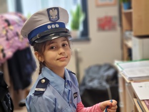 uśmiechnięta dziewczynka w mundurze i w czapce policyjnej na głowie