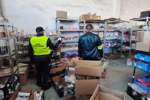 policjant i funkcjonariusz służby celno-skarbowej w pomieszczeniu z nielegalnymi towarami na półkach i kartonach