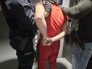 dwaj policjanci prowadzą zatrzymanego skutego w kajdanki