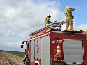 strażacy stoją na wozie strażackim