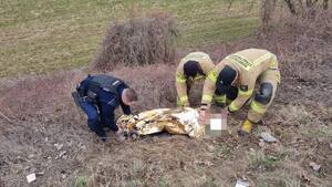 policjant i dwóch strażaków otulają kocem termicznym odnalezioną osobę