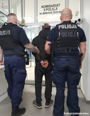 prowadzenie zatrzymanego mężczyzny przez policjantów w mundurach