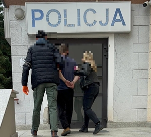 policjantką i policjant wprowadzają zatrzymanego do budynku policji