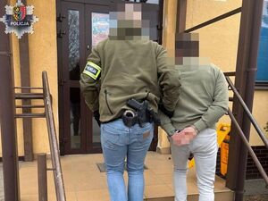 POLICJANT PROWADZI ZATRYZMANEGO SKUTEGO W KAJDANKI