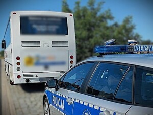 policyjny radiowóz a przed nim biały autobus