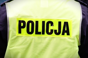 Napis Policja na odblaskowej kamizelce policjanta
