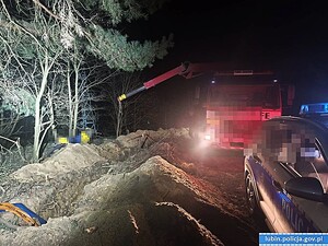 Na pierwszym planie radiowóz, a w tle dźwig wyciągający motocykl.