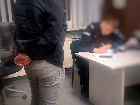 policjant podczas sporządzania dokumentacji z zatrzymanym