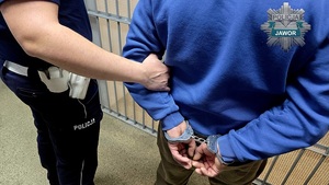 policjant prowadzi zatrzymanego