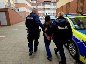 Policjanci prowadzą zatrzymaną do radiowozu