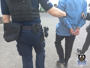 policjanci  prowadzą zatrzymanego mężczyzne