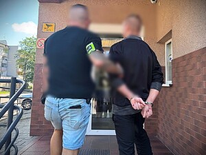 policjant prowadzi skutego w kajdanki zatrzymanego