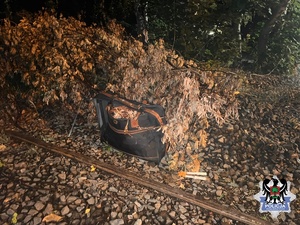 Torba tekstylna koloru czarnego położona na ziemi. Z wnętrza torby wystają przewody miedziane.