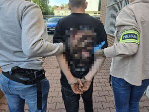 policjanci prowadzą zatrzymanego mężczyznę do budynku komendy