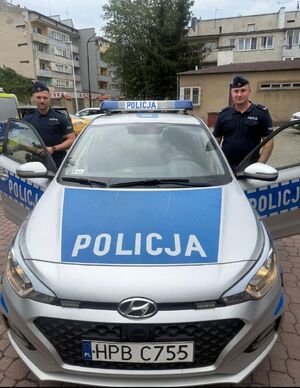 Umundurowani policjanci stoją przy radiowozie.