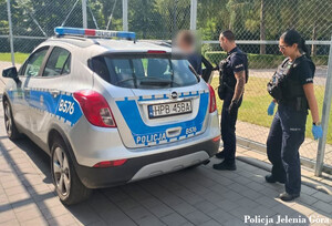 policjanci prowadzą zatrzymanego do radiowozu
