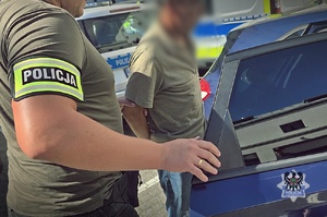 policjant prowadzi zatrzymanego