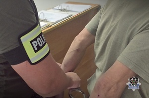 policjant prowadzi zatrzymanego