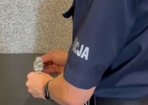 POLICJANT TRZYMA ZEGAREK W RĘCE