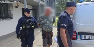 Policjanci prowadzą zatrzymanego do radiowozu