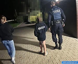 Policjant w mundurze idący z dzieckiem ubranym w policyjna kurtkę