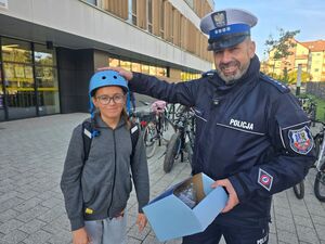 policjant rozdaje kaski