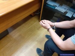 Zatrzymany mężczyzna w kajdankach na rękach.