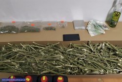 Susz pociętej konopi indyjskiej znajdujący się w kartonie obok banknoty po 100 zł, 10 zł oraz przygotowana do sprzedaży marihuana umieszczona w woreczkach.