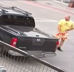 Na zdjęciu kolejny mężczyzna  podejrzewany o popełnienie przestępstwa ubrany w żółtą koszulkę i kolorowe krótkie spodenki stojący koło terenowego czarnego samochodu.