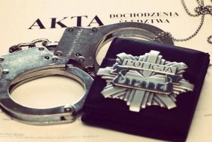 Kajdanki i odznaka policyjna leżące na aktach