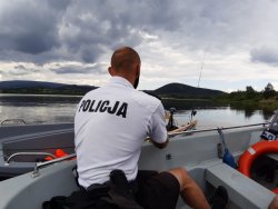 Policjant siedzący na łodzi policyjnej podczas patrolu wodnego