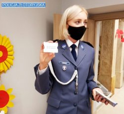 Policjantka w maseczce ochronnej,  prezentuje specjalne etui na kartę płatniczą