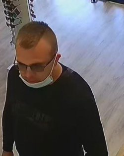 Zdjęcie poszukiwanego mężczyzny w maseczce ochronnej złożonej na brodzie, w okularach i ciemnej bluzie -