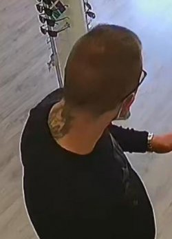 Zdjęcie poszukiwanego mężczyzny w ciemnej bluzie stojącego tyłem z tatuażem na karku