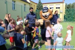 Grupka dzieci wita się z Komisarzem Lwem, maskotką dolnośląskiej Policji i policjantami w mundurach