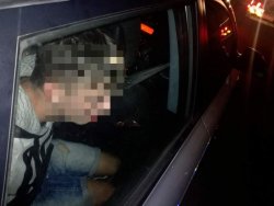 Zatrzymany nietrzeźwy kierujący siedzący skuty w kajdankach w policyjnym radiowozie