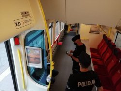 Dwóch policjantów w pociągu kontrolujący pasażera pod kątem przestrzegania nowych obostrzeń