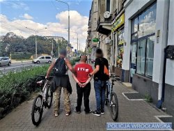 Na zdjęciu dwóch wrocławskich (ubranych po cywilnemu) policjantów na rowerach zatrzymują na ulicach Wrocławia mężczyznę