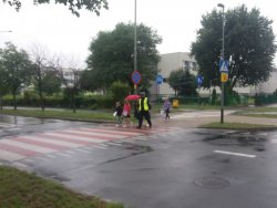 policjant przeprowadza bezpiecznie dzieci na drugą stronę ulicy.
