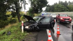 Na zdjęciu pojazd osobowy uszkodzony w wyniku zderzenia, w tle ulica i jadące samochody.