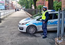 Na zdjęciu policjant stojący przy radiowozie, pełniący służbę w rejonie al. Wyzwolenia w Wałbrzychu.